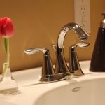Bathroom washbasin with chrome tap and a red flower